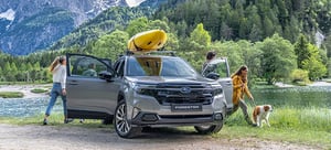 Familie mit Hund und Forester mit Kajak auf dem Dach