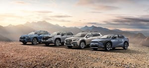 Vier verschiedene Subaru-Modelle in Blau- und Grautönen nebeneinander auf einem Bergplateau mit Bergpanorama.