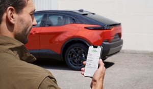 Mann mit Smartphone vor einem Subaru Uncharted in orange
