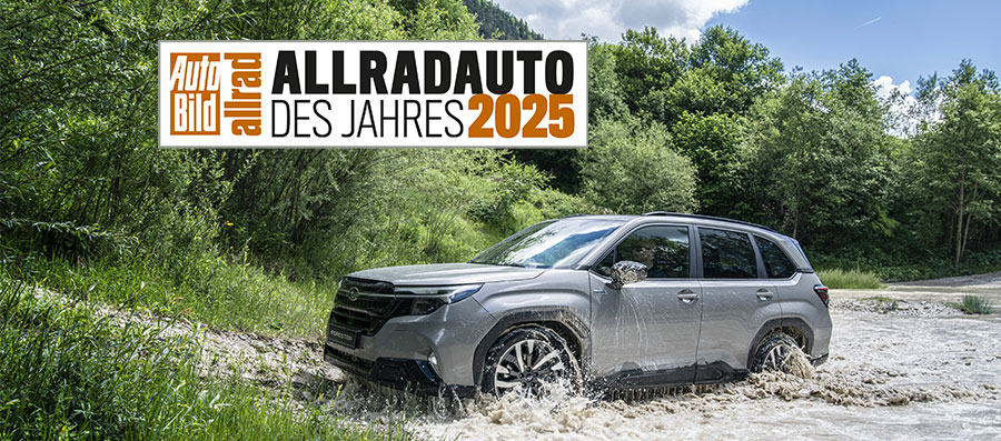 Auto Bild Allradauto des Jahres 2025 Badge und darunter ein Subaru Forester der gerade einen Fluss durchquert hat mit Wald im Hintergrund.